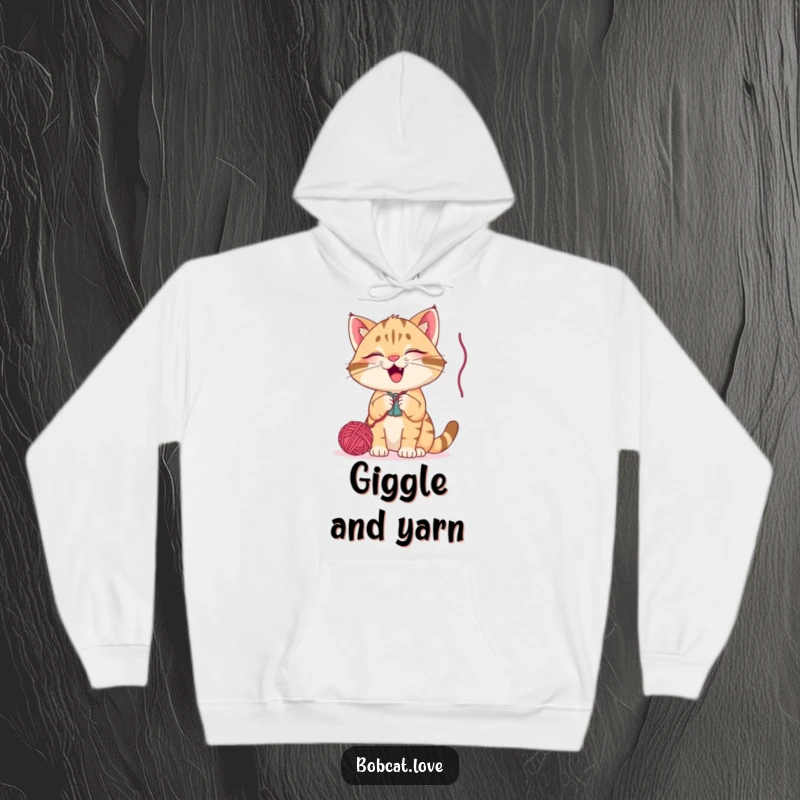 Funny bobcat hoodie, a happy cat batting playfully at a dangling yarn ball, radiating cozy, humorous, and adorable feline energy.