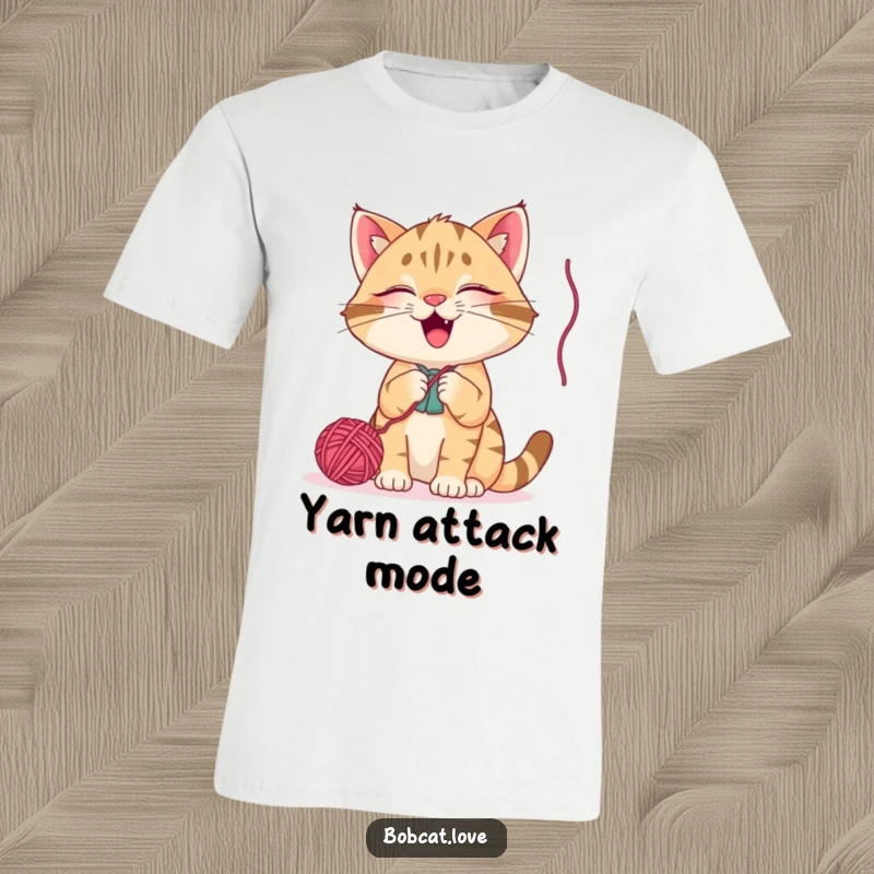 Funny bobcat t-shirt, a giggling wild cat playfully batting at a dangling yarn ball, depicting a moment of pure, comical kitty joy.